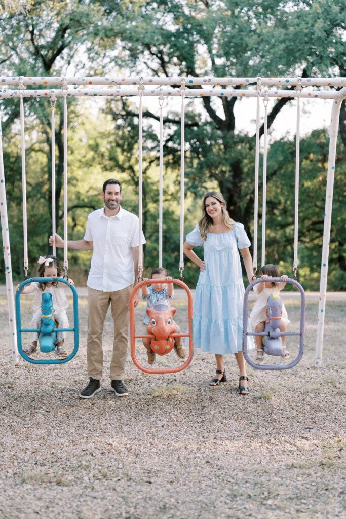 family at playground, parents stand by while kids swing taken by Story-Driven Family Photography in Colorado Springs