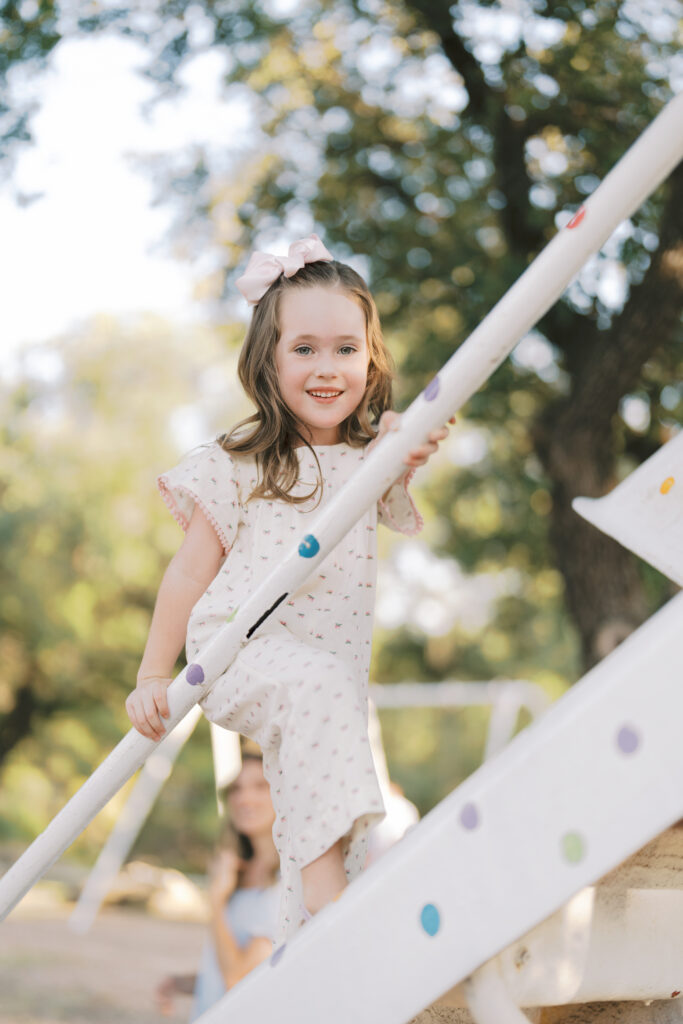 sister smiling big at top of stairs at playground