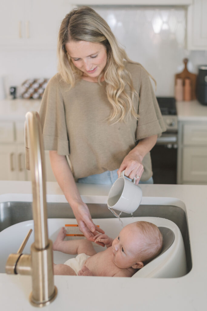 mom giving baby a bath in kitchen sink