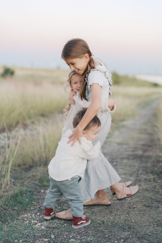 three siblings embracing and hugging oldest sister taken at a Colorado Springs family session by Lauren Bounds Photography