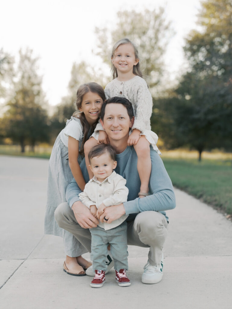 three kids posing with dad, one in front, one on side, and one on shoulders