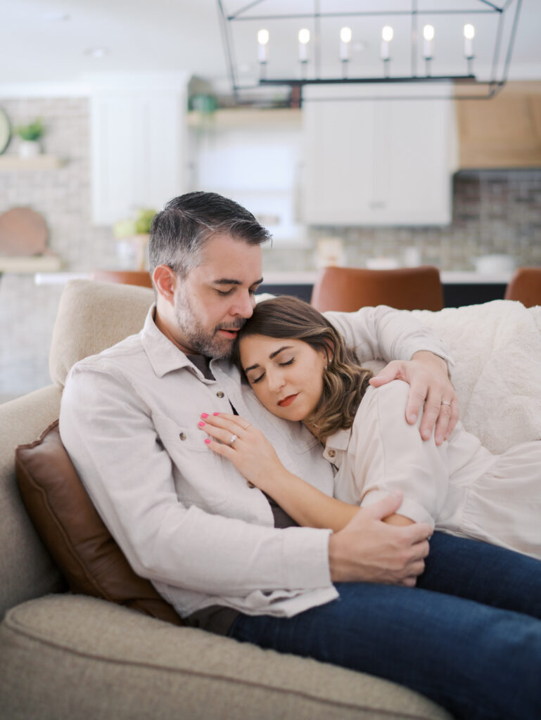 mom and dad snuggling on couch for family photos in Colorado Springs