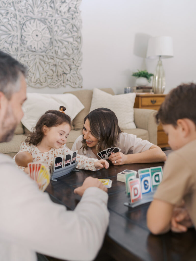 mom and daughter laugh close while playing the game uno
