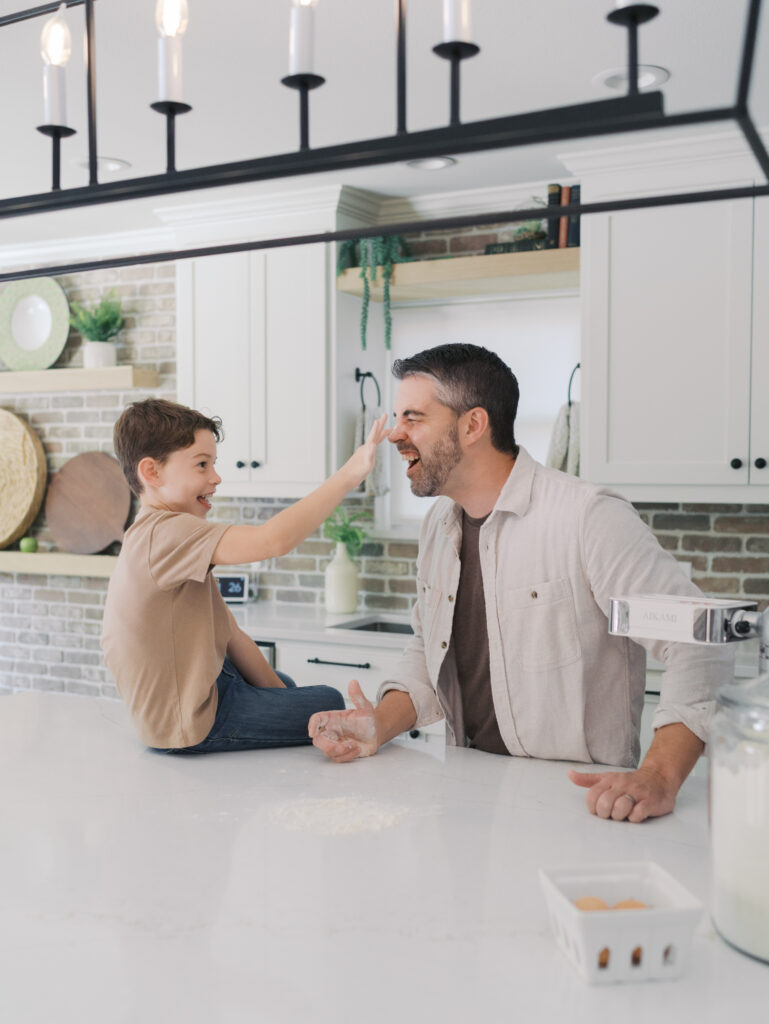 boy putting flour on dad's nose in kitchen for Colorado in home family session