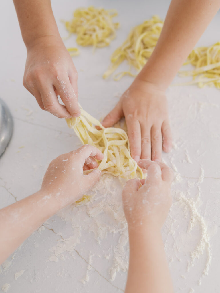 little hands holding homemade uncooked pasta noodles