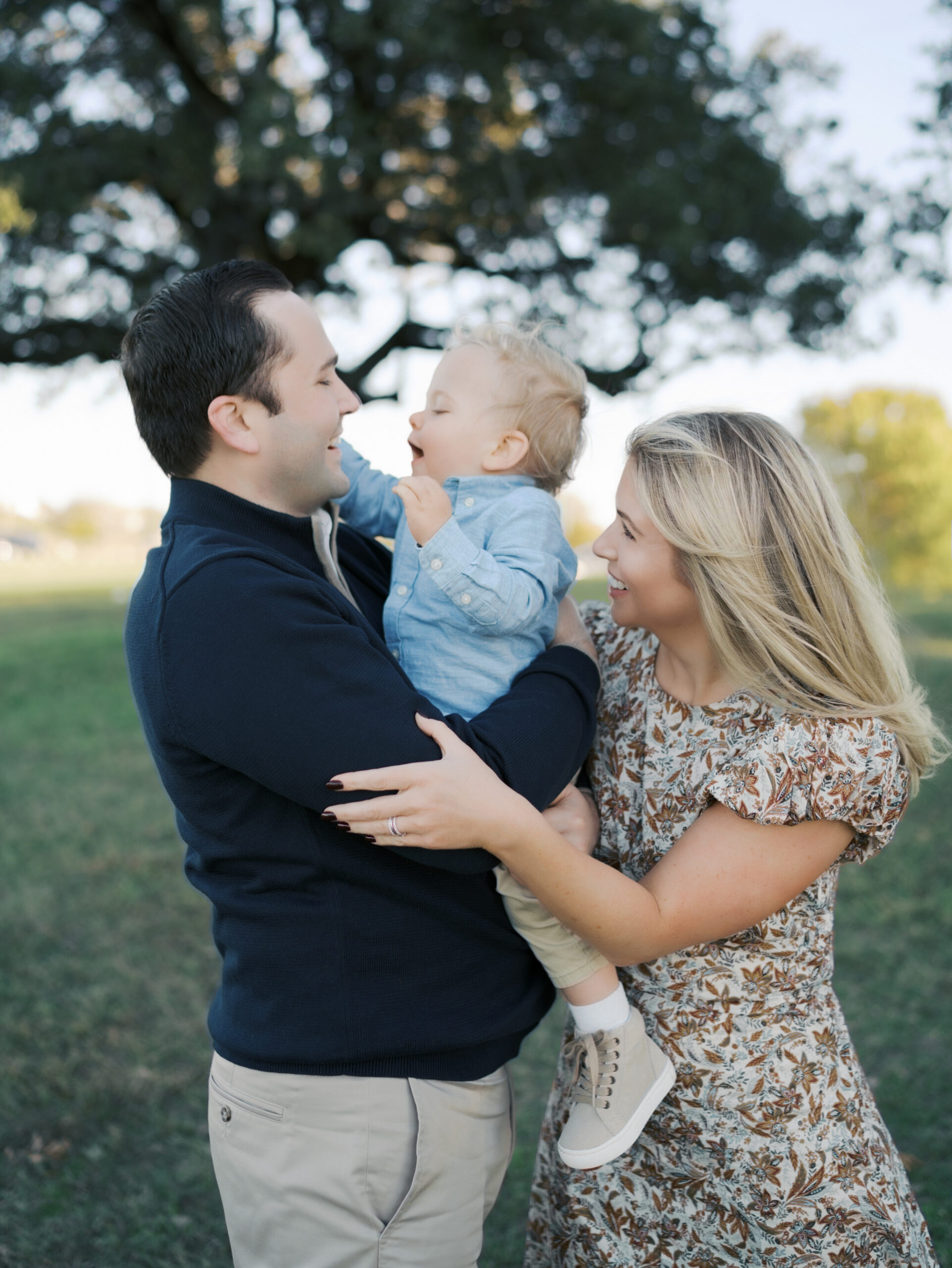 Dad holding bot in arms face to face laughing while mom hugs from behind showing Fall Color Palettes for Photos
