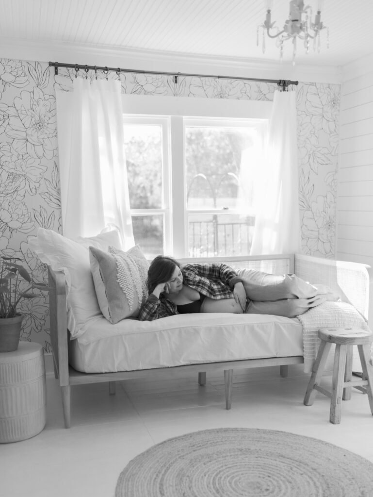 Expecting mom gazing at pregnant belly on daybed