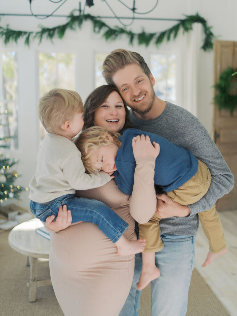 expecting family with two young boys in parents arms snuggling for maternity photos in Colorado Springs, CO