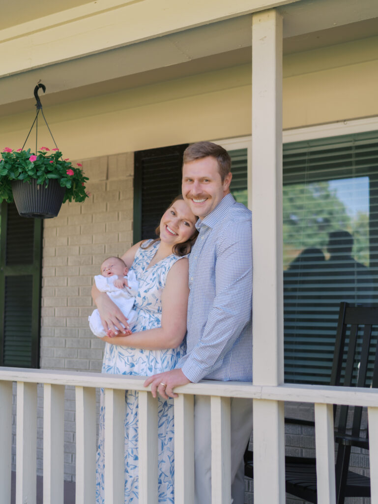 parents on porch with newborn smiling