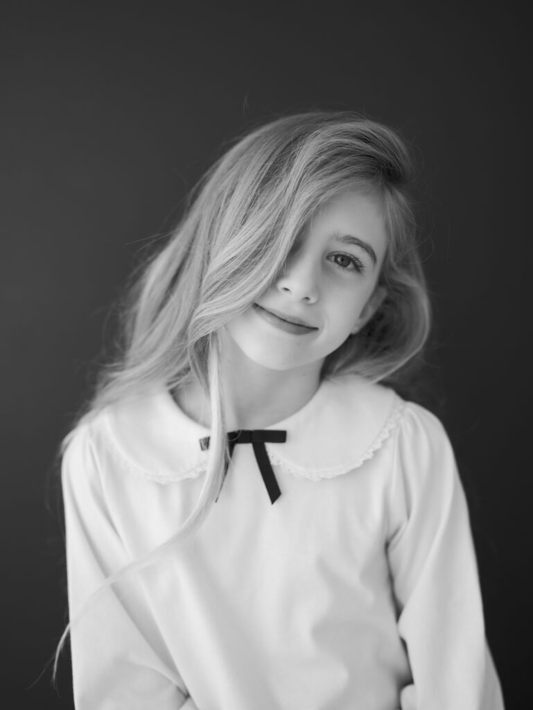 older girl smiling in front of black backdrop