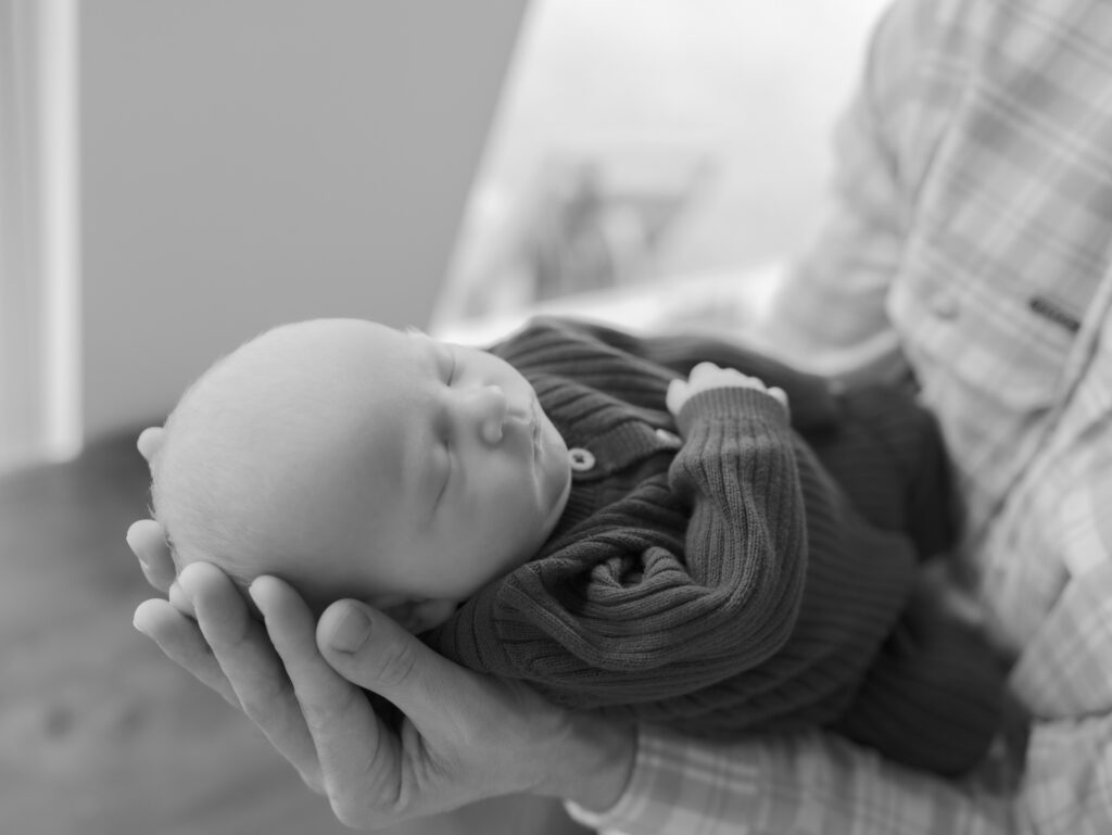 newborn in dad's arms and hands Take better photos at home | Colorado Springs Newborn Photographer