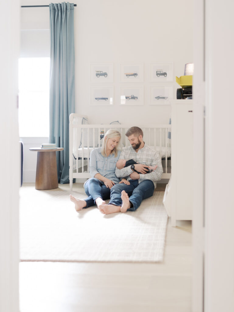 parents sitting on floor of nursery with newborn