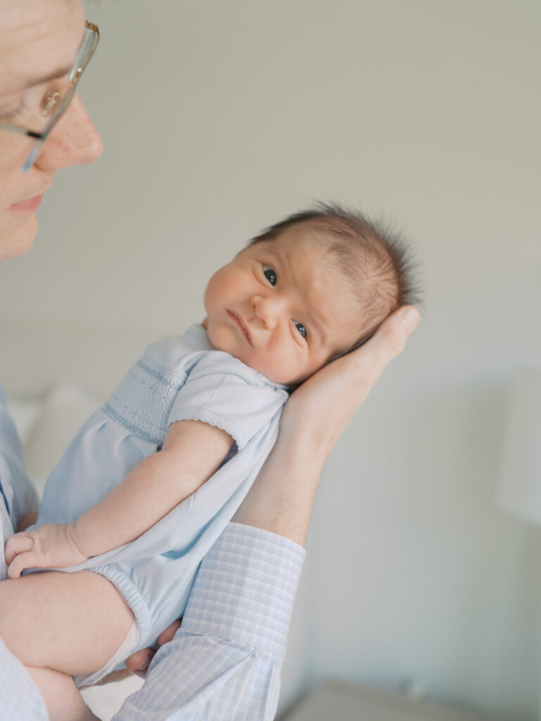 newborn looking at camera in dad's arm