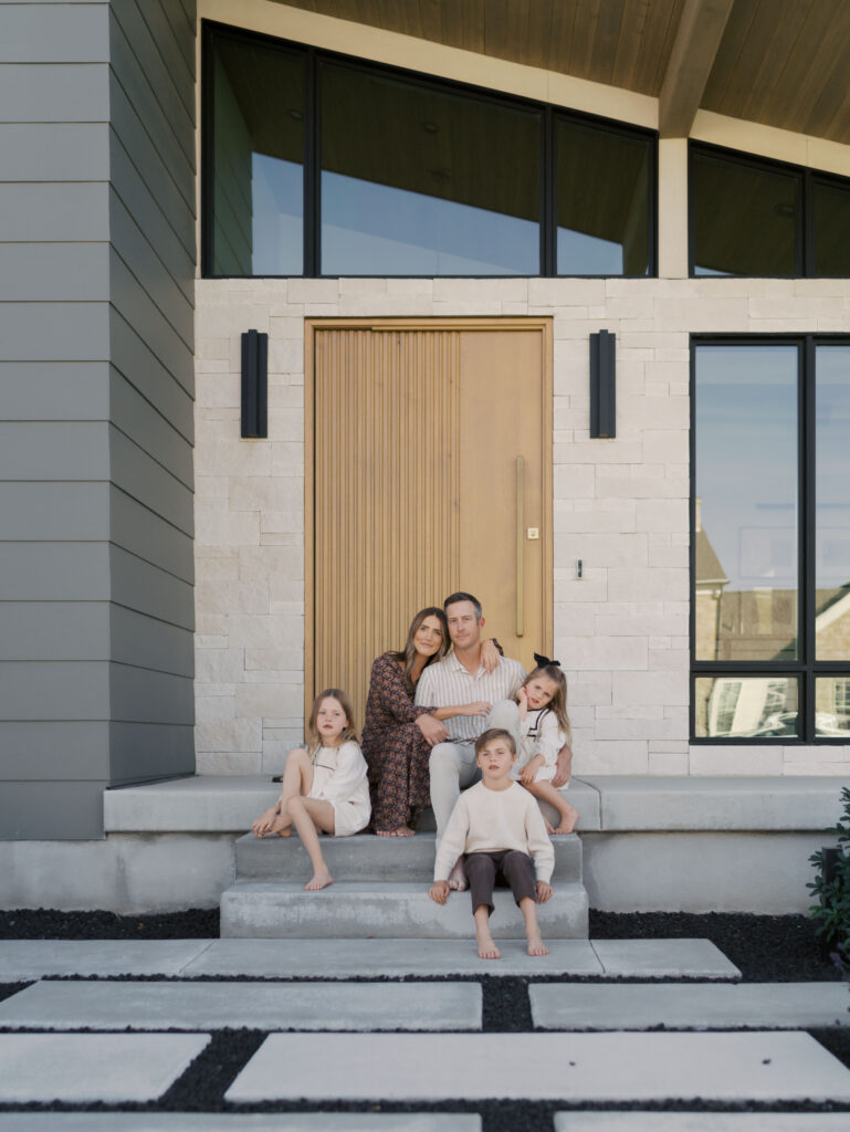 family of five on porch in front of house sitting for colorado springs family photos