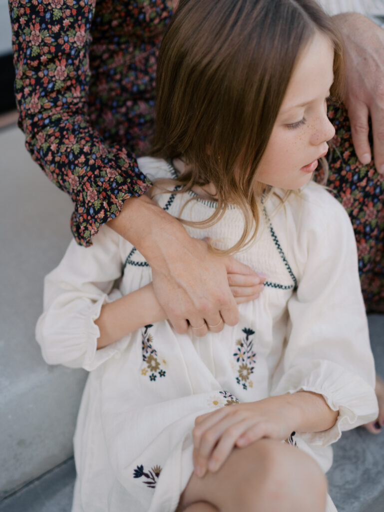 mom holding daughter's hand as she leans against her