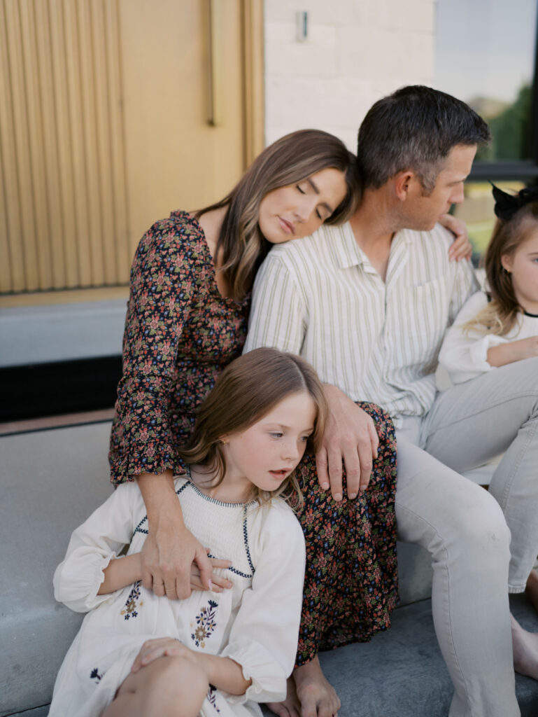 mom holding daughter's hand as she rest her head against husband