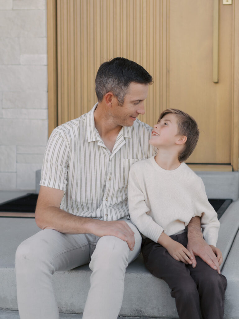 dad and son looking at each other while sitting on porch