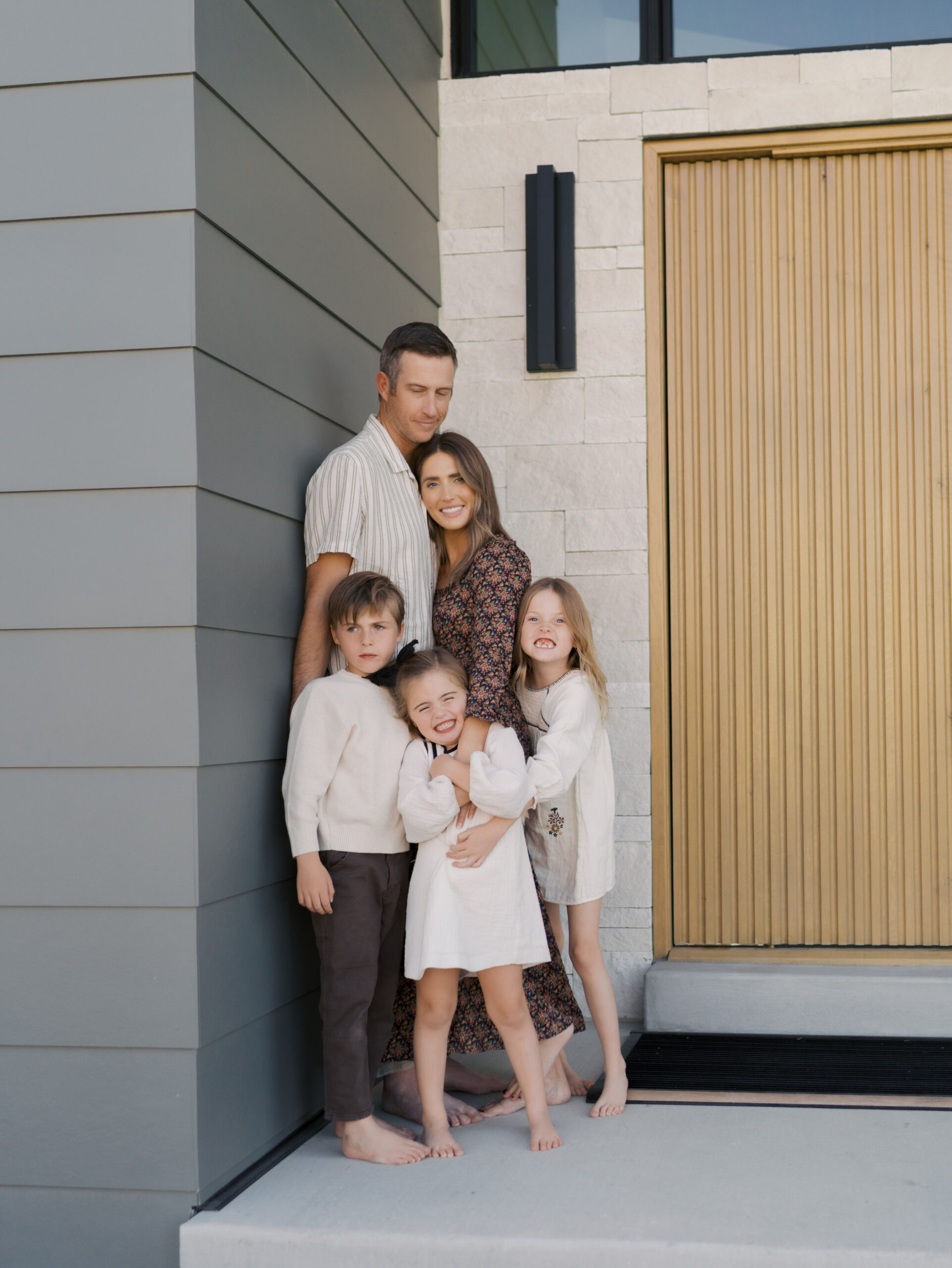 Family of five on their front porch snuggle close to show how to coordinate family photo outfits