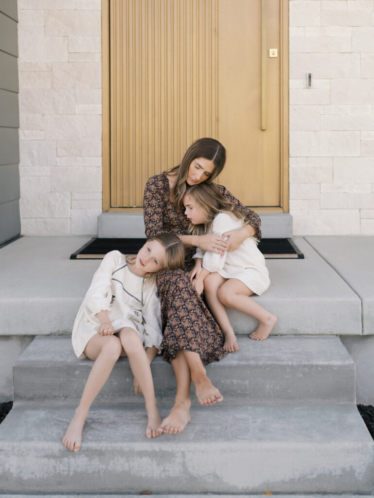 mom snuggling girls on front porch