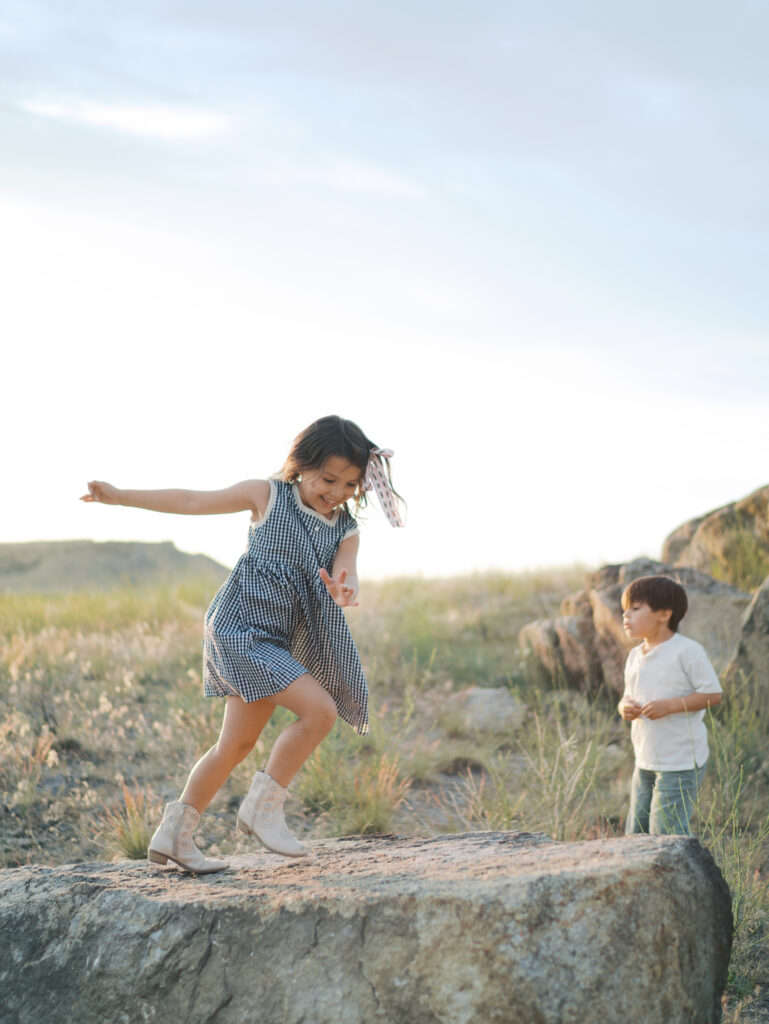 Little girl running on huge flat rock while little brother watches. Moment captured by Family Photographer Colorado Springs.