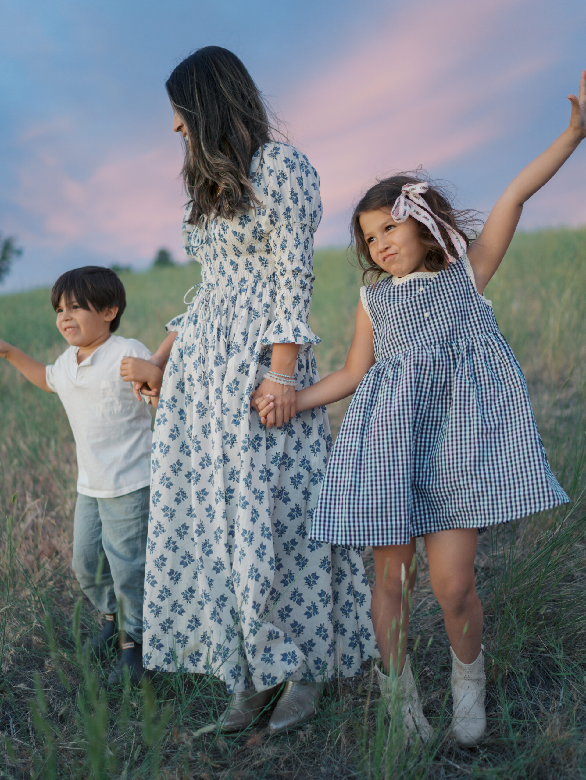 mom with two kids dancing at beautiful sunset