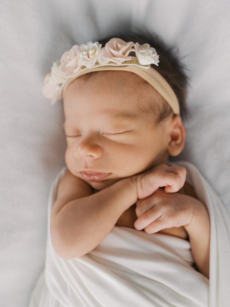 Sweet Newborn baby swaddled and wearing white floral headband capture by | Colorado Springs Newborn Photography | Lauren Bounds Photography
