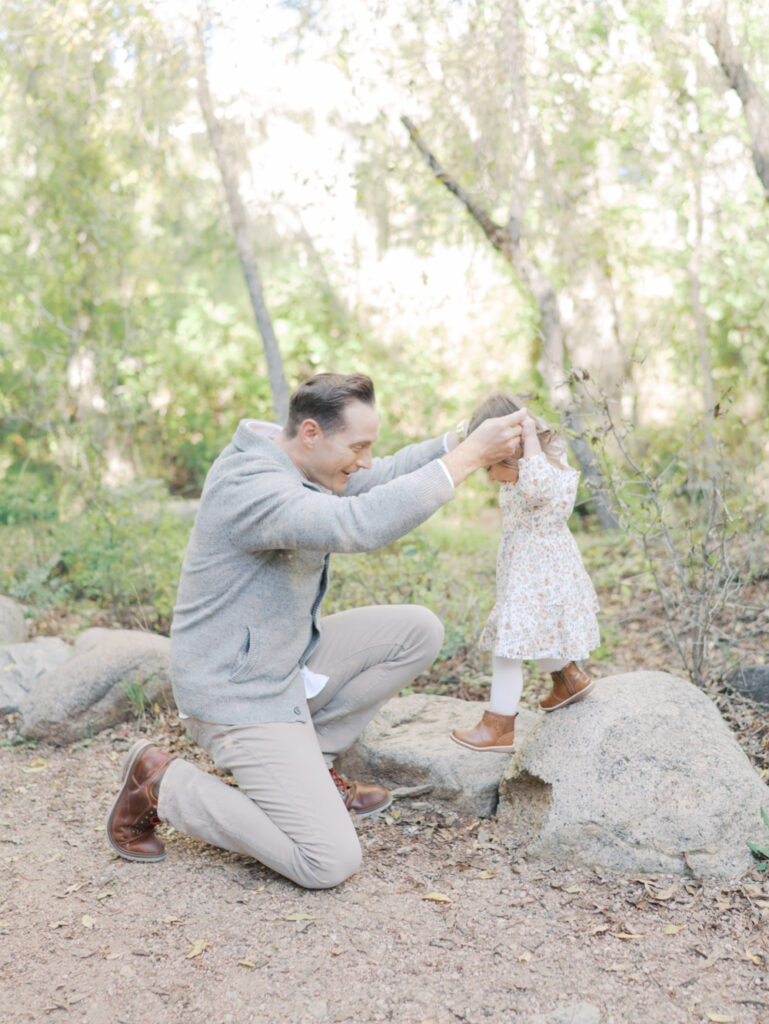 dad helping toddler daughter off a rock at Bear Creek Nature Center during a Colorado Springs Family Photo session