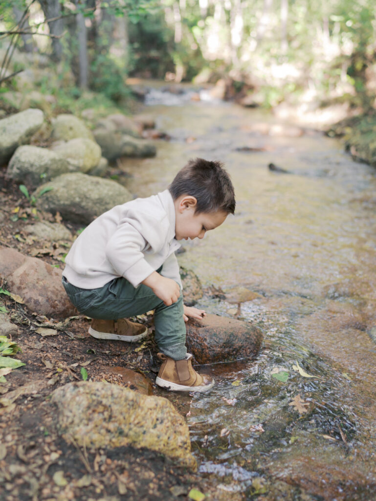 Little boy dipping his toe in a stream at Colorado Springs Family Photo session at Bear Creek Nature Center Taken by Lauren Bounds Photography