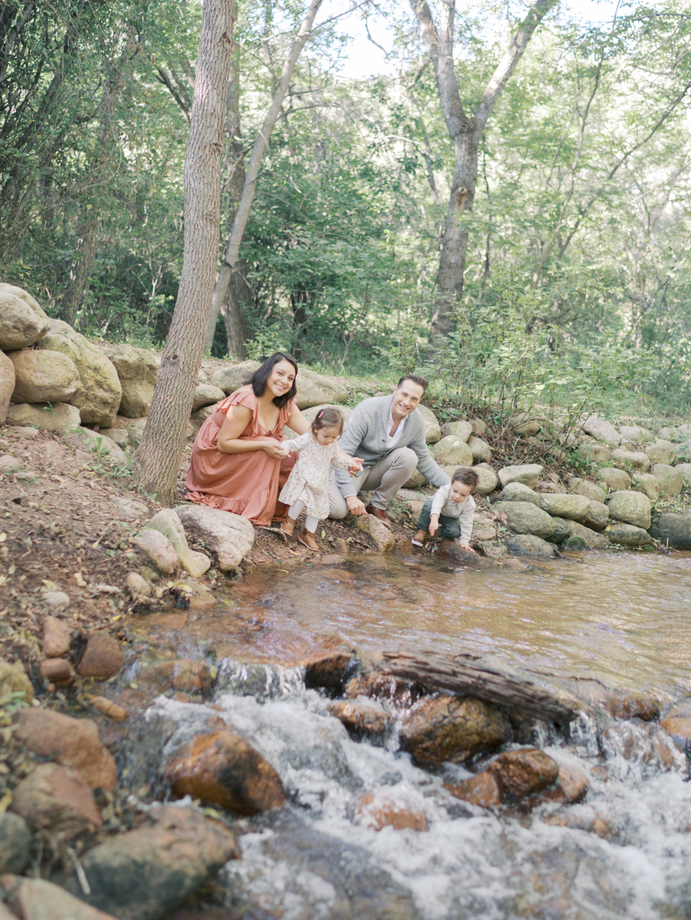 Family of four by stream, kids playing in water at Adventure family session in Colorado Springs