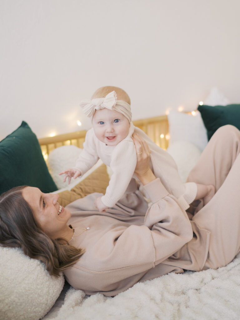 mom laying on bed with baby looking at camera taken at a photo studio in Colorado Springs