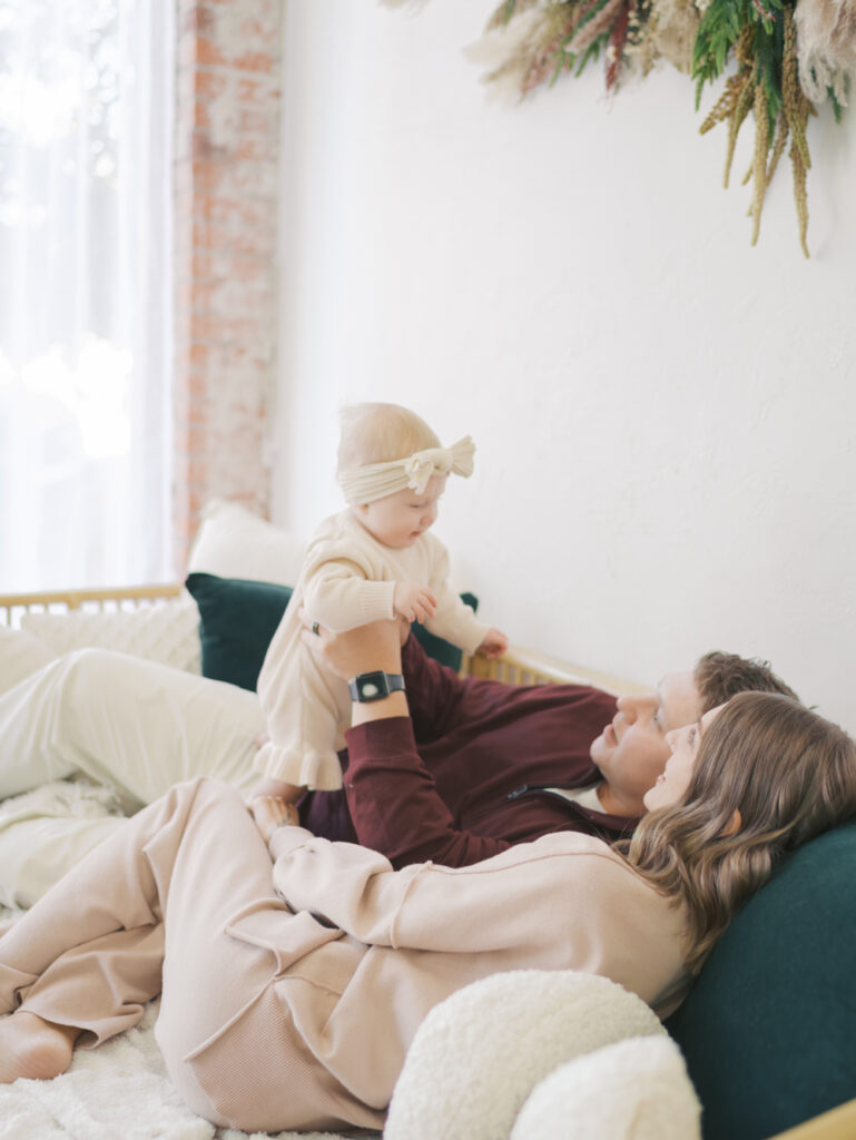 couple laying on bed with baby at photo studio in Colorado Springs by family photographer colorado spring lauren bounds