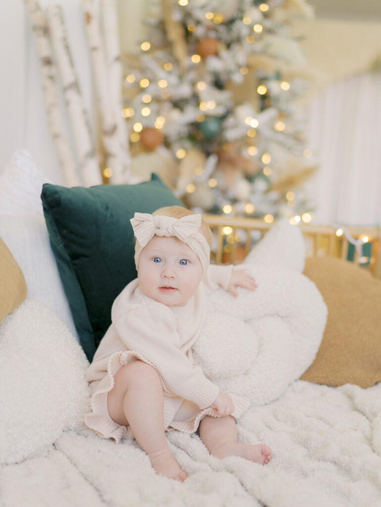 baby sitting bed infront of christmas tree at a photo studio in Colorado Springs by Family Photographers in Colorado Springs
