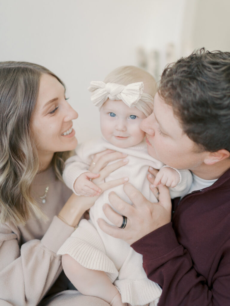 mom and dad kissing baby's cheek at a photo studio in Colorado Springs by Lauren Bounds Photography