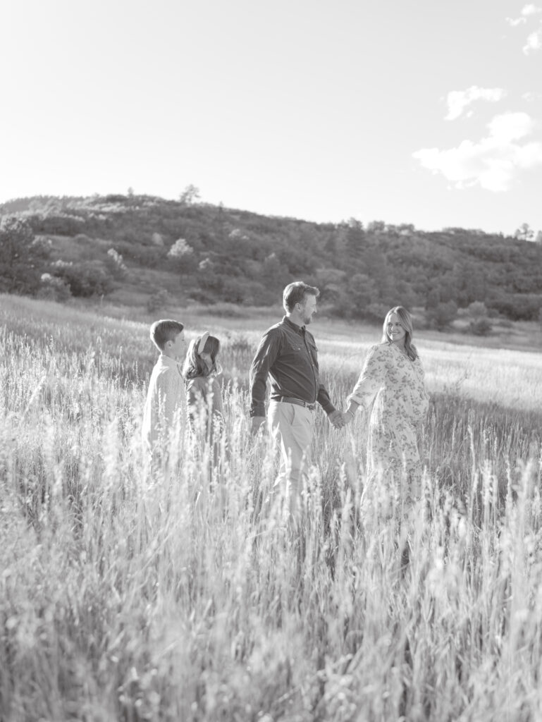 family of four walking in field in black and white