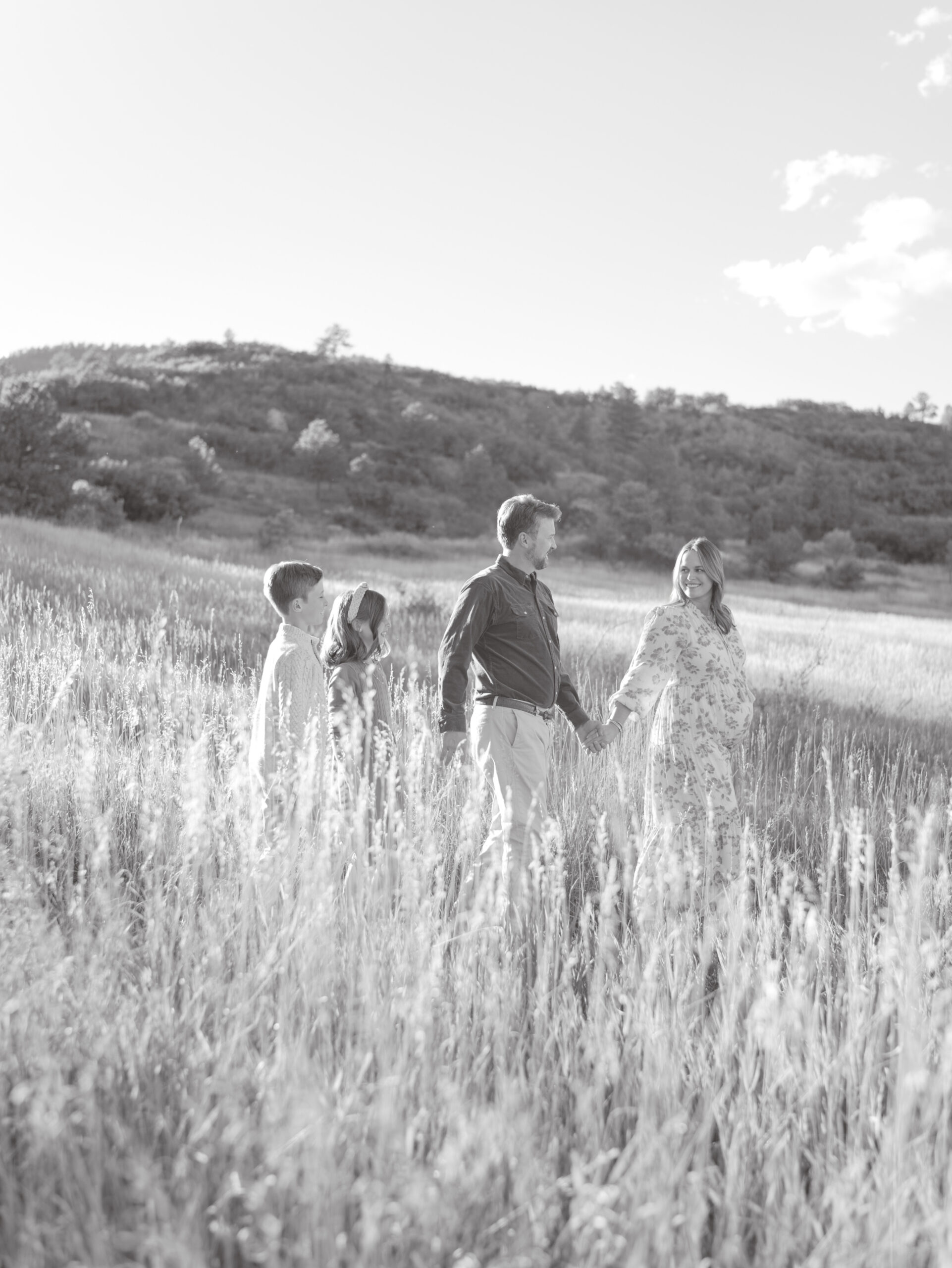 family of four walking in field in black and white