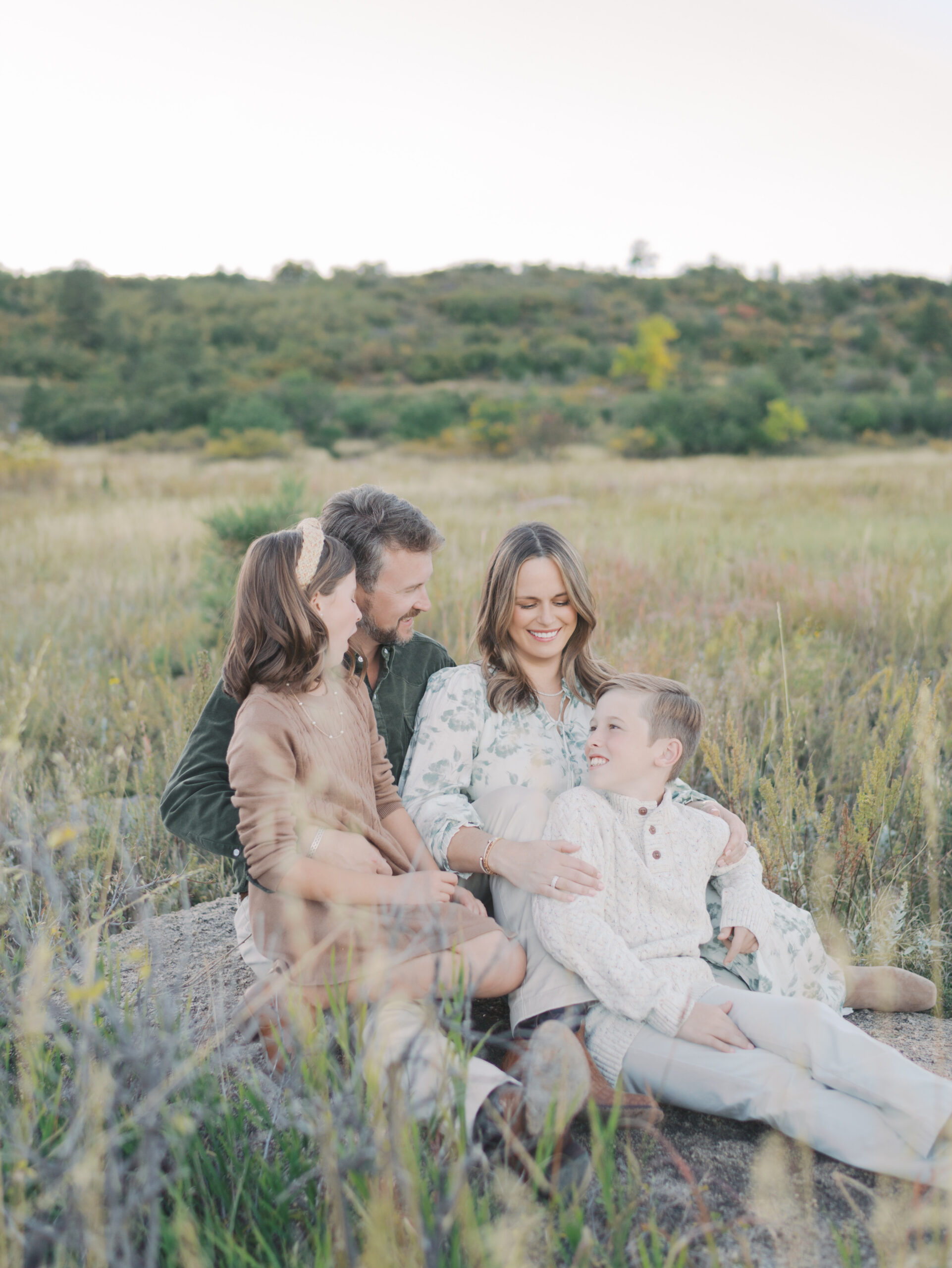 family of four sitting on a rock snuggled together taken by Colorado Springs Maternity Photographer Lauren Bounds