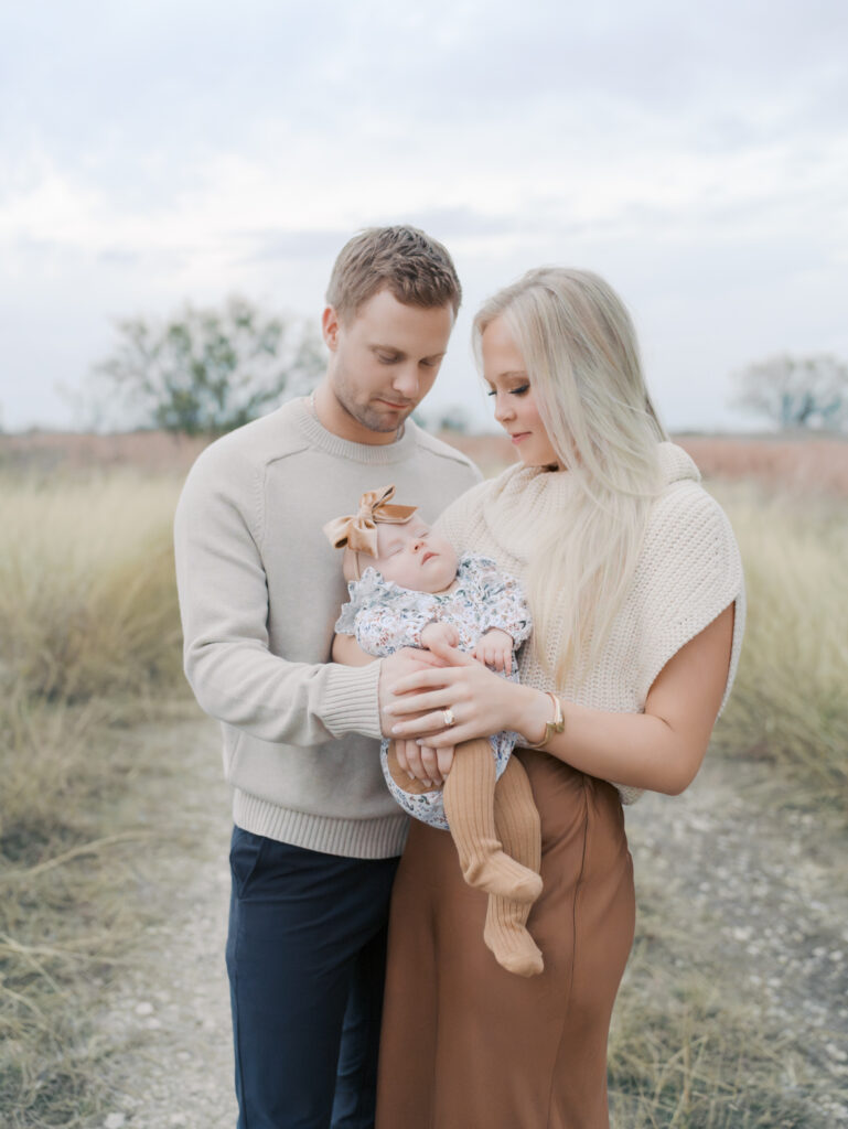 family of three close and holding hands around baby at Outdoor Newborn Session in Colorado Springs