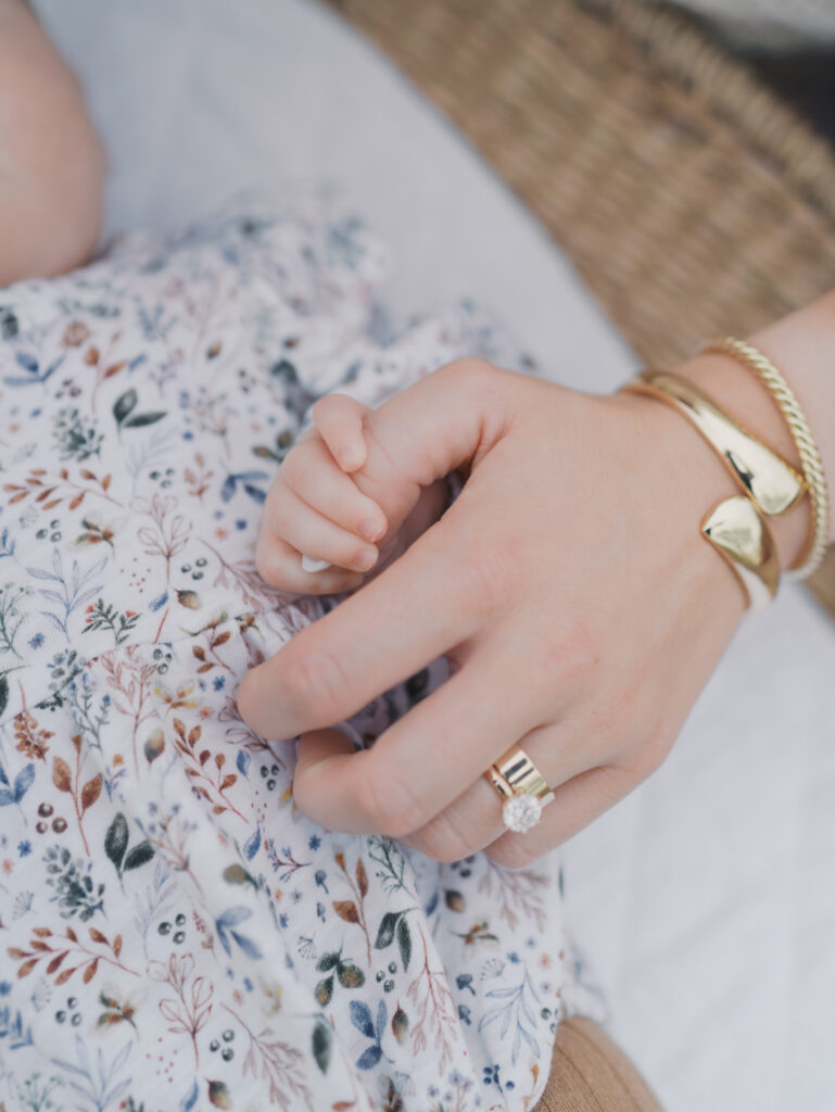 moms hand with baby's wrapped around her thumb by colorado springs newborn photographer