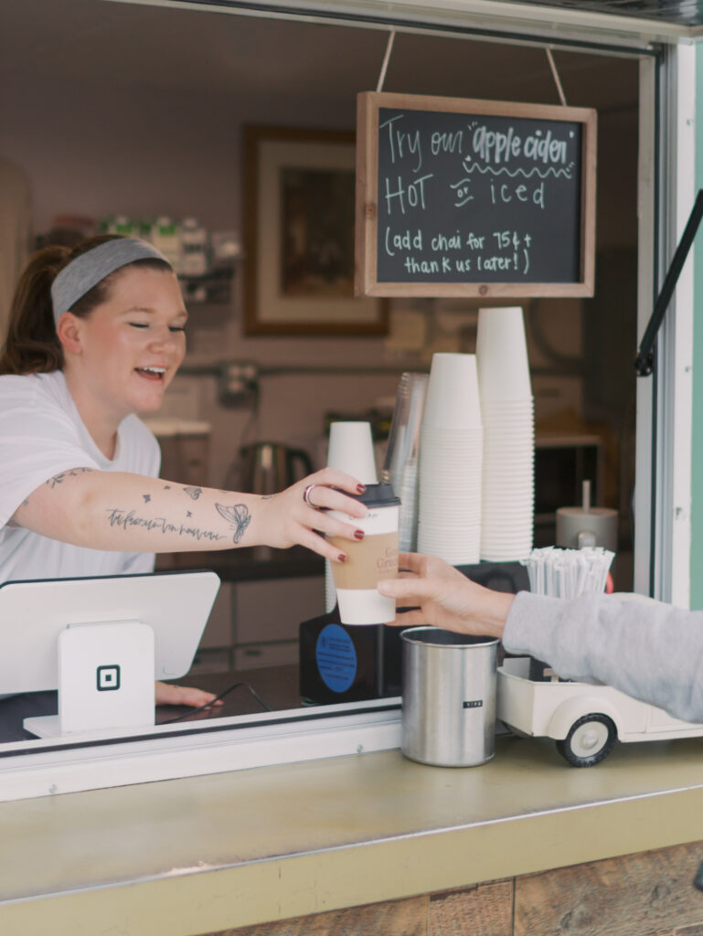 Grace handing coffee to customer