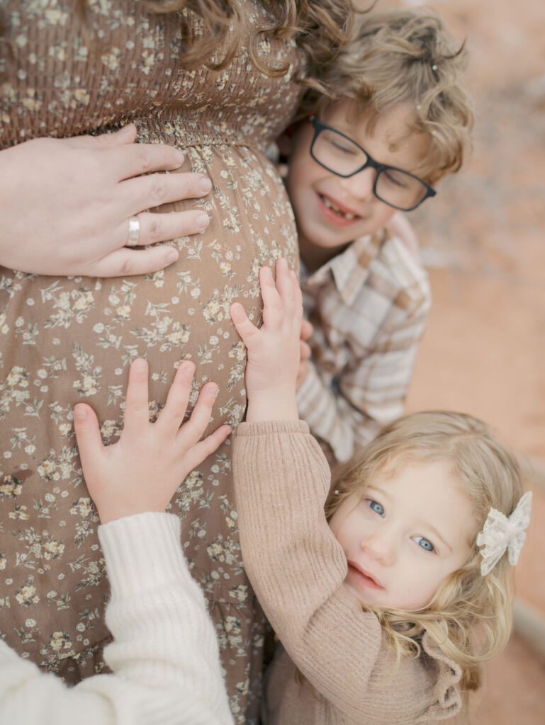 kids hugging mom's pregnant belly at garden of the gods for a maternity photo session