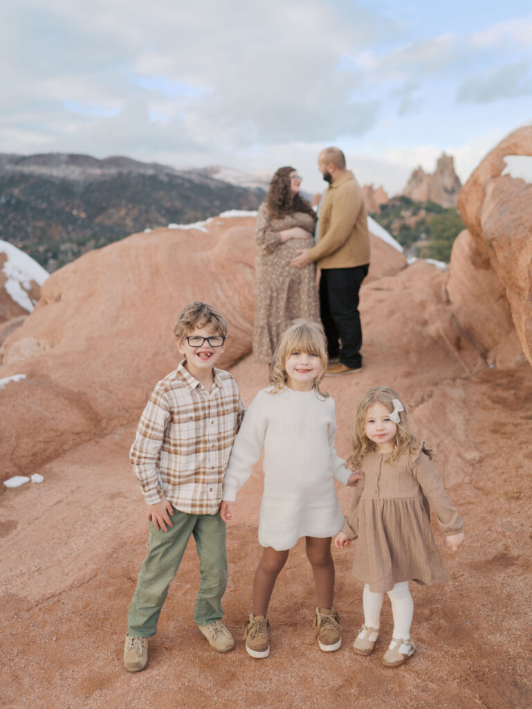 kids looking at camera with parents in the background at garden of the gods