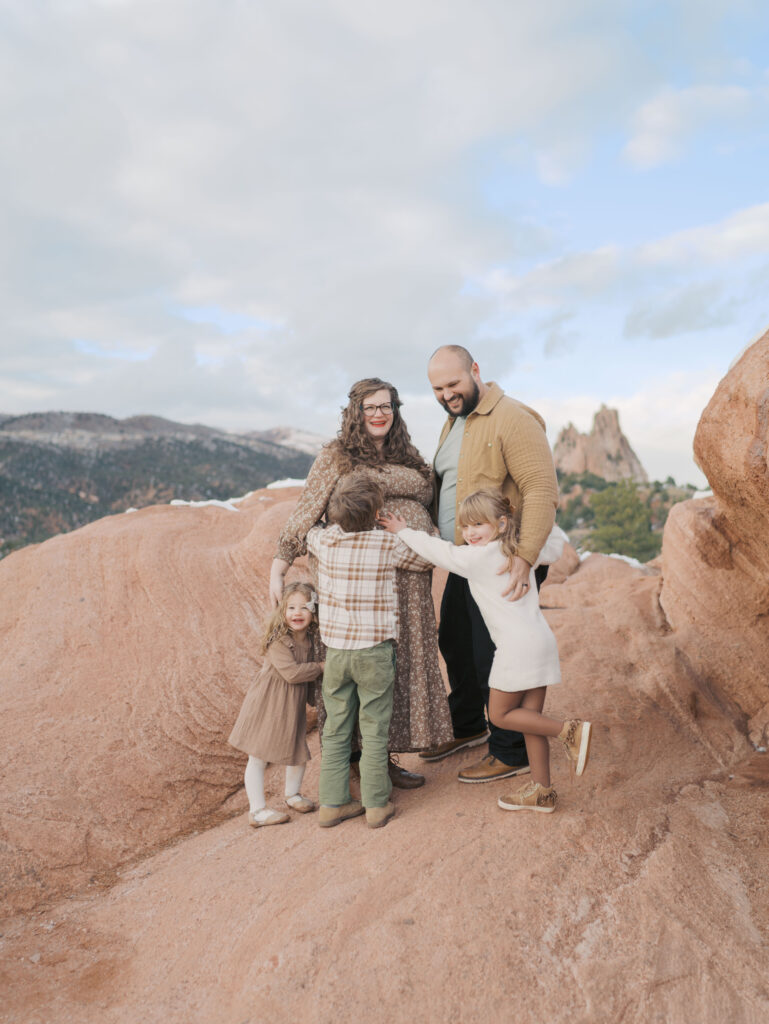 Garden of the Gods Photography maternity session showing family of five with iconic background hugging