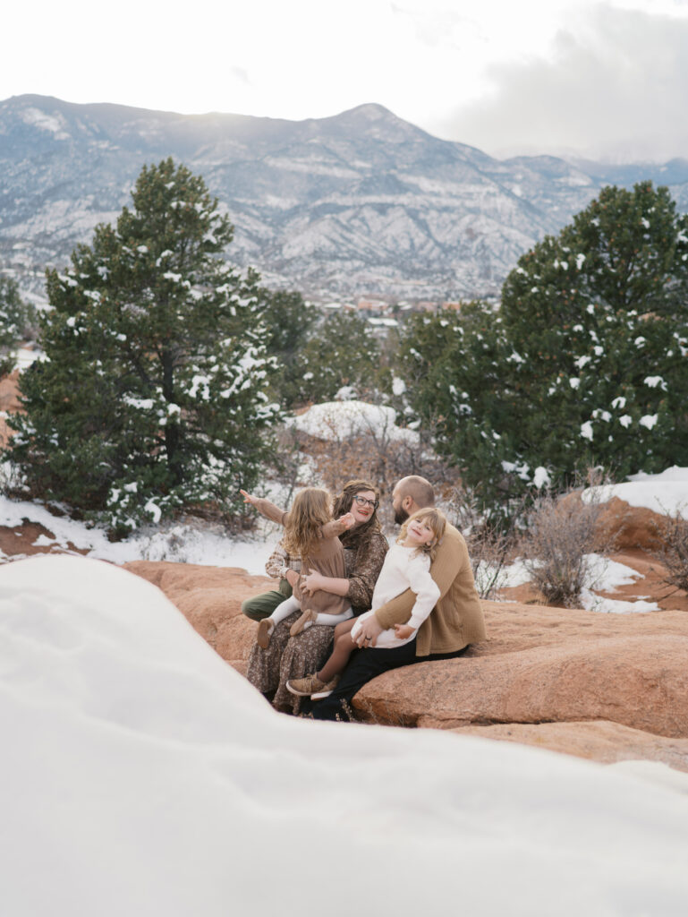 family gather on red rocks at garden of the gods during a maternity session in colorado springs showing what to wear for maternity photos