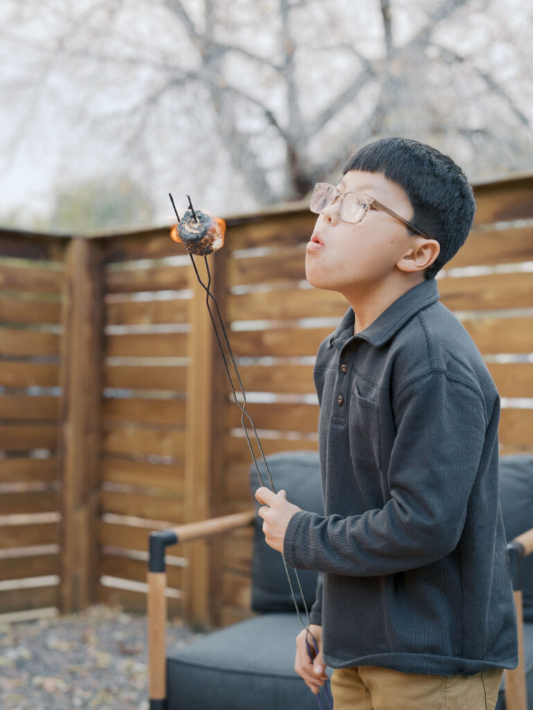boy blowing out roasted marshmallow that is on fire 