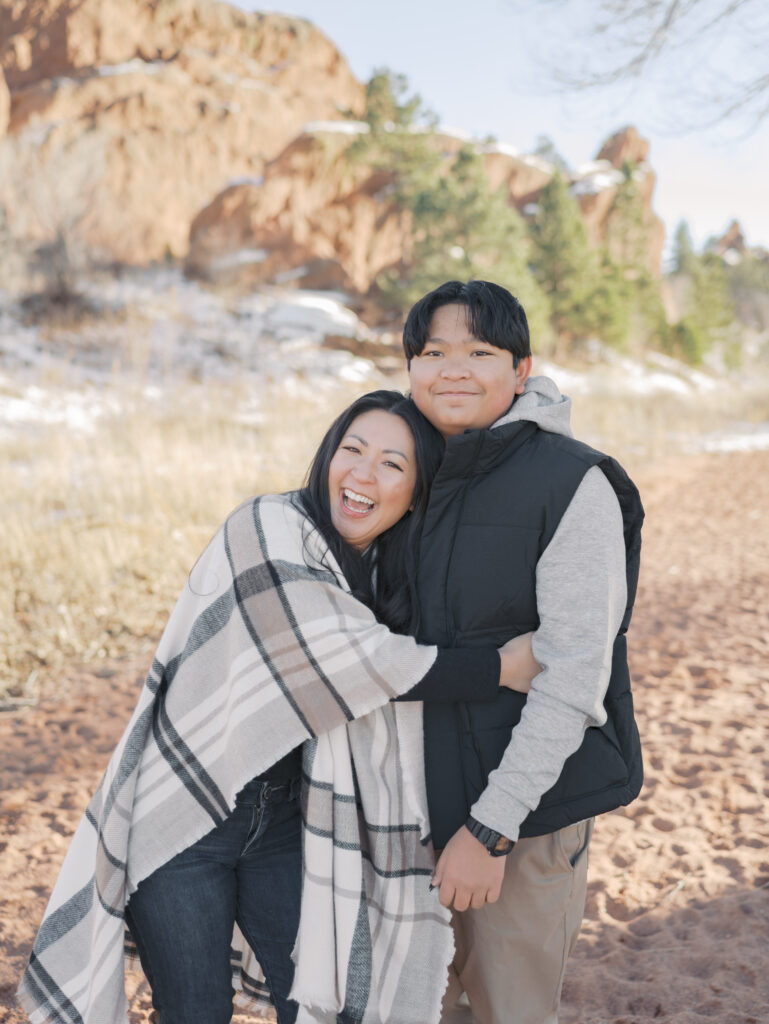 mom hugging teen son smiling big during colorado springs family photo session