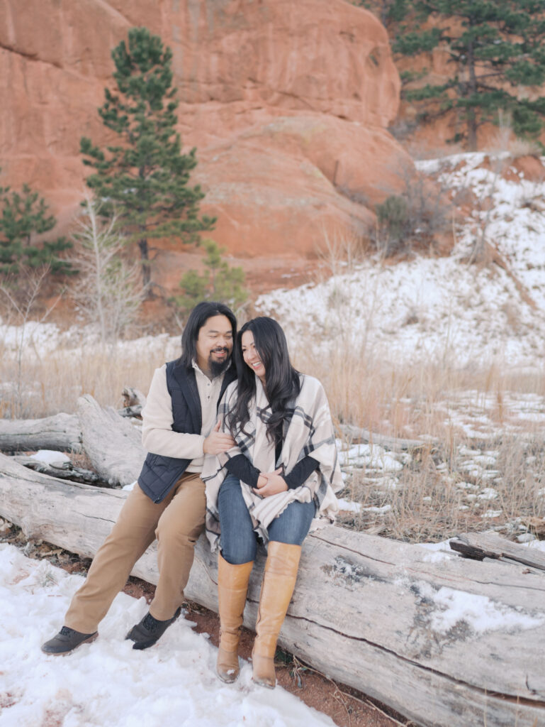 couple sitting on log together embracing at red rock open space