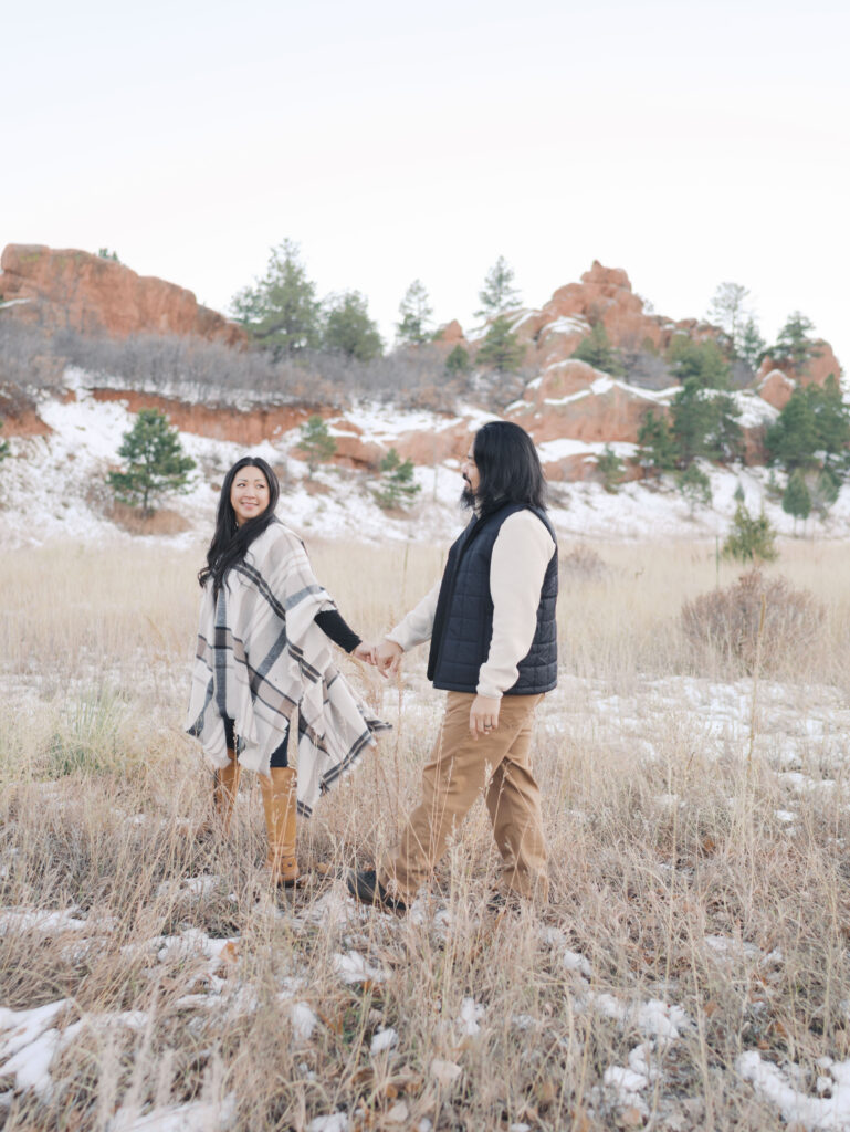 couple walking and holding hands at red rock open space in colorado springs during family photo session
