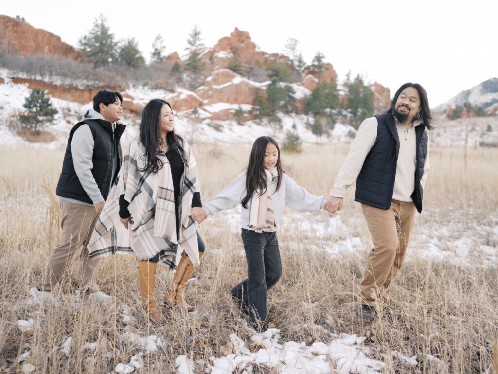 family walking and holding hands in a line ar red rocks during colorado springs photography