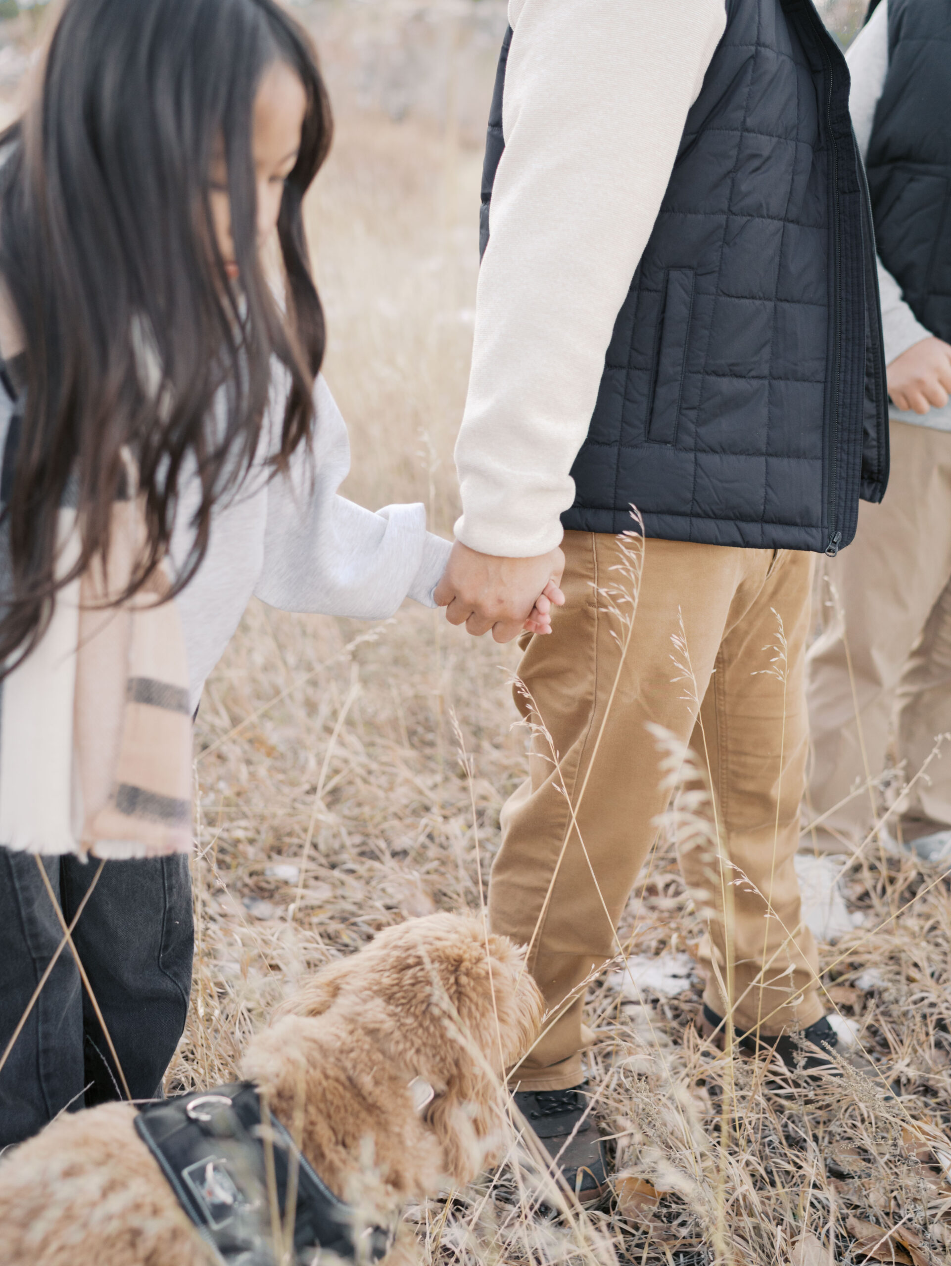 close up of daughter holding dad's hand while walking at red rock open space,