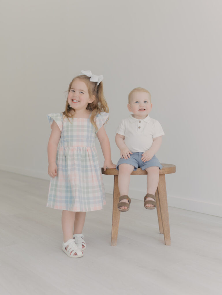 sister stand nexts to little brother on stool for sibling mini sessions colorado springs